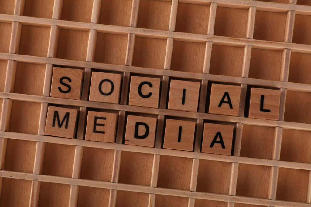 Close-up of wooden letter blocks spelling 'Social Media' on a wooden grid.